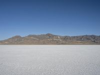 mountains surround a wide plain covered with snow in the background, and a clear sky