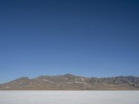 mountains surround a wide plain covered with snow in the background, and a clear sky