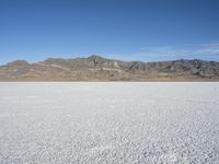 mountains surround a wide plain covered with snow in the background, and a clear sky