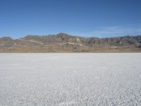 mountains surround a wide plain covered with snow in the background, and a clear sky