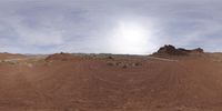 a 360 - lens photo of a mountain and a dirt road and red rocks under the sky