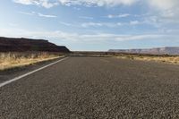 a empty desert highway with mountains and hills in the background, with yellow lines drawn across the roadway