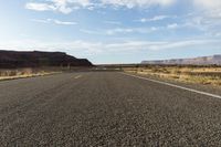 a empty desert highway with mountains and hills in the background, with yellow lines drawn across the roadway