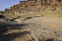 a large canyon covered in rocks and sand near the water's edge during the day