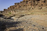 a large canyon covered in rocks and sand near the water's edge during the day