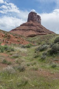 a view of a mountain with a trail in the middle with bushes around it, and a blue sky above