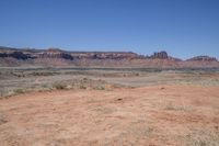 an empty dirt road that is next to some mountains with large rocks in the background