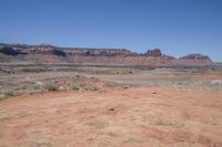 an empty dirt road that is next to some mountains with large rocks in the background