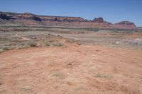 an empty dirt road that is next to some mountains with large rocks in the background