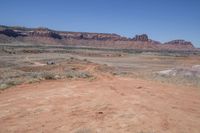 an empty dirt road that is next to some mountains with large rocks in the background