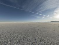 a lone snowboarder in the middle of nowhere under a cloudless sky is pictured on a beach