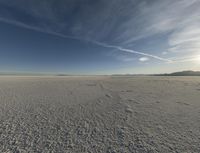 a lone snowboarder in the middle of nowhere under a cloudless sky is pictured on a beach