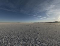 a lone snowboarder in the middle of nowhere under a cloudless sky is pictured on a beach