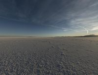 a lone snowboarder in the middle of nowhere under a cloudless sky is pictured on a beach