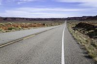 a lonely highway with an arrow painted on it and bushes growing out of the pavement