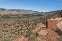 a view from the top of a mountain with a large rock in the foreground