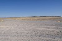 an area with a dirt field, sand and water on the horizon is dry grass