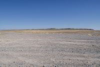 an area with a dirt field, sand and water on the horizon is dry grass