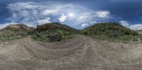 a camera angle shot with a dirt track through the desert with clouds in the background