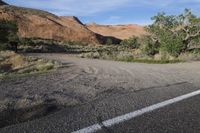 a desert area with a lone street in it and a lone sign near a forest