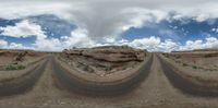 a 360 - view photo of a wide street in the desert near rocks and a cloudy sky