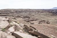 a man riding a motorcycle down a dirt hillside side by side with rocks in the background