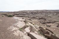 a man riding a motorcycle down a dirt hillside side by side with rocks in the background