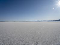 the snow is melting on the open desert plain and sun shines on the horizon