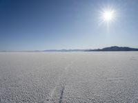 the snow is melting on the open desert plain and sun shines on the horizon