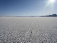 the snow is melting on the open desert plain and sun shines on the horizon