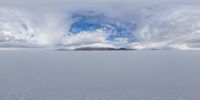 a lone horse is walking across the vast open field that leads to an island beneath the clouds