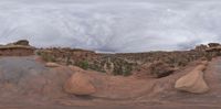 the rocks in the foreground are eroded out into an unusual shape and the sky is cloudy with a small dot of clouds