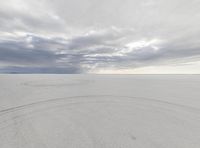 a snowboarder rides the snowy surface on the open plain with clouds above him