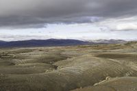 an image of a desert scene with mountains in the background under a cloudy sky with white clouds