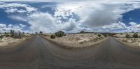 some dirt and rocks in front of a cloudy sky with a dirt road in the middle