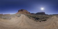 an 360 - turn view of some rocks in the distance at sunrise as seen from below a dirt road