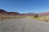 a highway winds through desert scenery with mountains in the background and blue sky above it