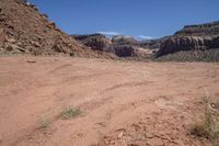 a dirt road in a canyon with lots of rocks on each side and grass in the middle