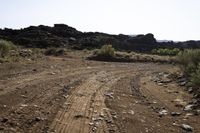 the dirt road is being cleared off by rocks and shrubs in the desert area next to an arch