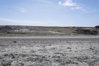 a dirt road is surrounded by some hills and desert like terrain as the vehicle sits on it