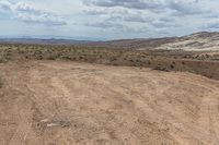 motorcycle driving in the dirt, through a dry wilderness area on a cloudy day with blue skies