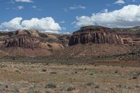 the wild horse is walking through the mountains and desert land near the mountains of the navajo