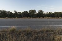 a long empty road with mountains in the distance with a car in the foreground