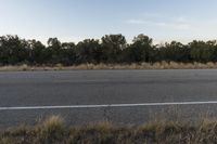 a long empty road with mountains in the distance with a car in the foreground