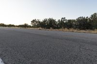 a long empty road with mountains in the distance with a car in the foreground