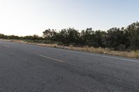 a long empty road with mountains in the distance with a car in the foreground