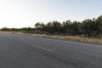 a long empty road with mountains in the distance with a car in the foreground