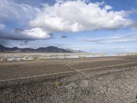 a lonely road stretches out into the desert with mountains in the background and water reflecting the ground