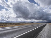 a cloudy sky above an empty highway in the middle of the day with clouds rolling