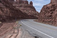 the road is winding into a canyon between rocky cliffs and cliffsides, with a sign marking an intersection that shows where to go